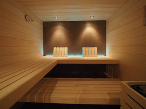 Das Spezielle an dieser Sauna in Espe mit Ganzglasfront ist die Akzentbeleuchtung an der rückwärtigen Innenwand. Sanatherm-Saunabau GmbH.