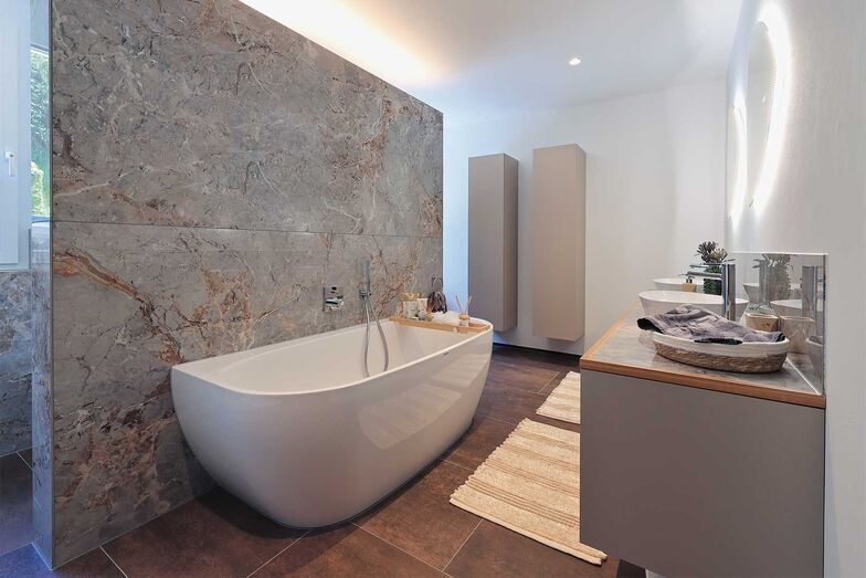 Die Natursteinwand teilt das Bad geschickt in verschiedene Nutzzonen.