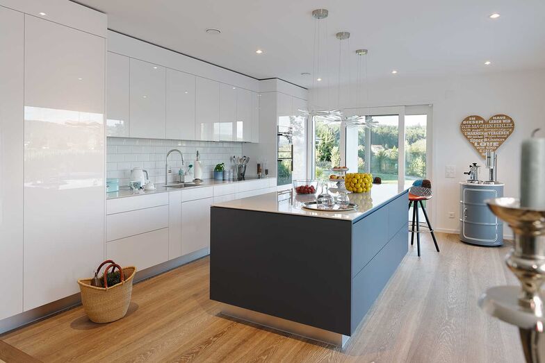 Mit ihren matt-dunklen Fronten ergänzt die Kochinsel die glänzend weisse Küchenzeile.