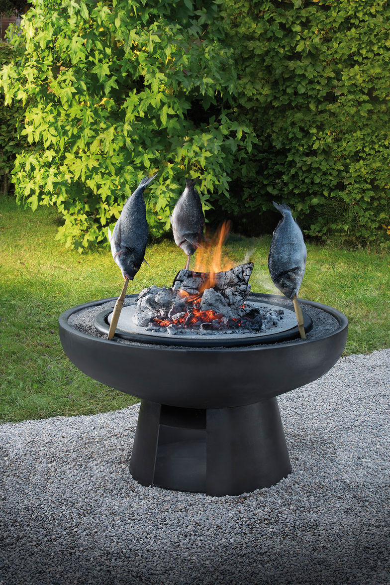 Fische am Spiess: Die Spiesse werden in den Sandring gesteckt, der die Feuerstelle umgibt. Der Fisch bleibt so rundum schön knusprig. Garten-Kulinarium GmbH.