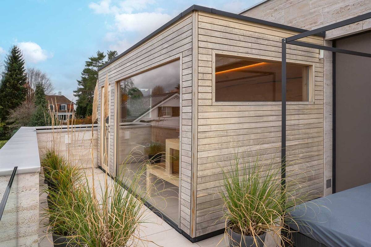 Diese massgefertigte Lösung von Sauna World passt perfekt auf die Terrasse. Die Sauna endet bündig zur Tür in die Wohnung und die Aussenverkleidung harmoniert mit der Hausfassade. So ist die Kabine kein Fremdkörper, sondern fügt sich gelungen in ihr Umfeld ein. Sauna World AG.