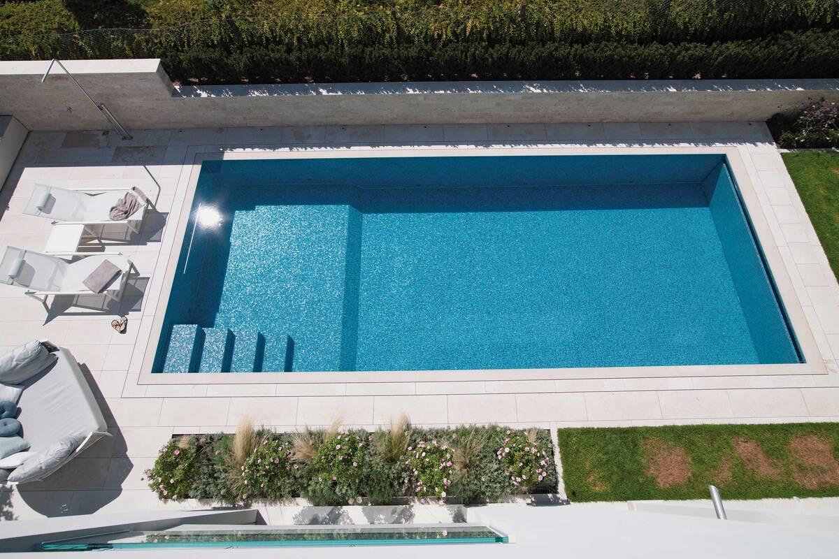 Zum Schwimmen und Relaxen: Zehn Meter langes Schwimmbecken mit Gegenstromanlage, Überlaufrinne und Massagestation. Innenverkleidung Bisazza-Glasmosaik, Umrandung Travertin-Natursteinplatten. Die Schwimmbadsteuerung reguliert Wasseraufbereitung, Heizung, Gegenstromanlage, Abdeckung und Beleuchtung. AC Schwimmbadtechnik AG.