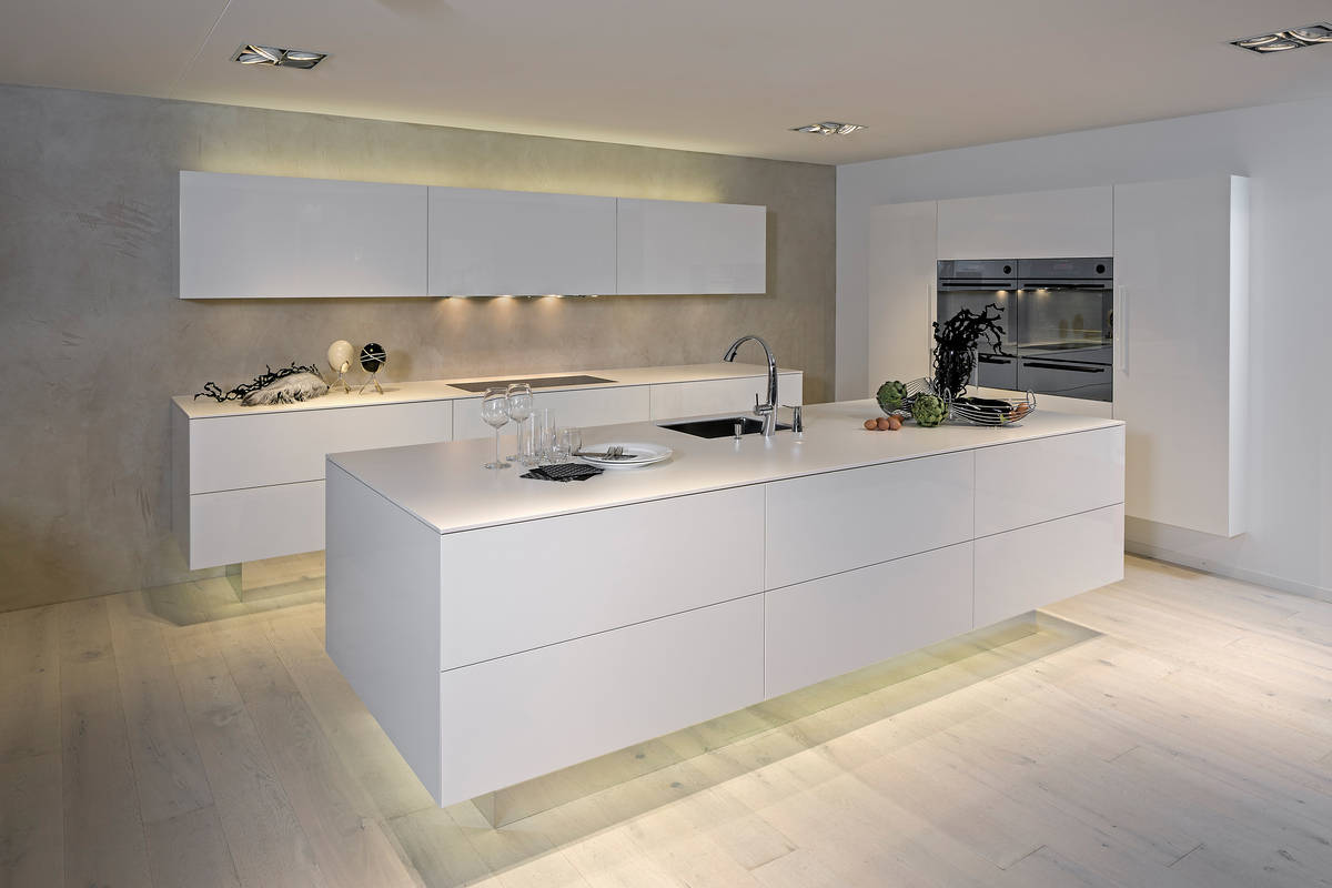 Der Sockel aus Spiegelglas ist ein stilbildendes Element dieses zeitlosen Küchenmodells aus Schongau. Furrer Küchen.