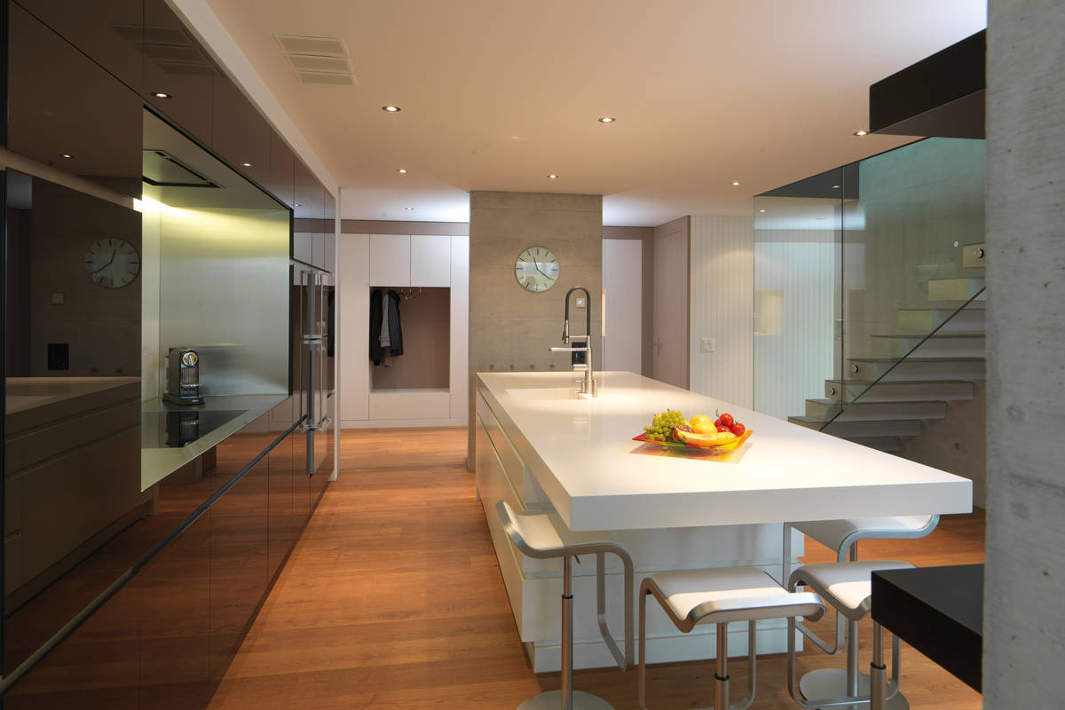 Koch-, Ess- und Wohnbereich gehen bei dem Gesamtkonzept Küche grenzenlos ineinander über. Die jeweiligen Funktionen werden mit massgefertigten Einbaumöbeln bedient. Kawa-Design.