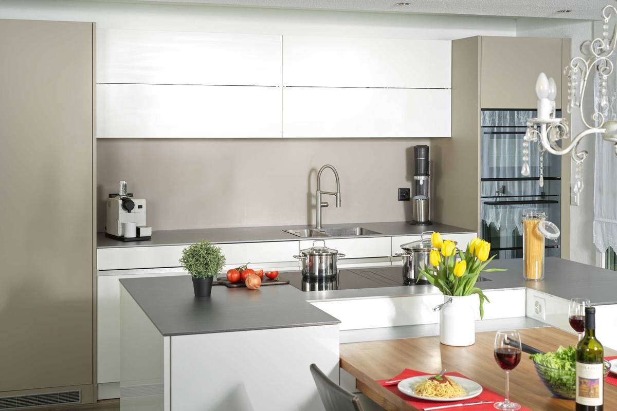  Platzsparend und praktisch ist die Idee, Kücheninsel und Esstisch zu einem Ensemble zu gruppieren. Natürliche Farben und Holz bilden eine harmonische Kombination. Veriset AG.