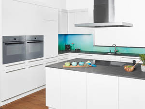 Der Hingucker: die grün-blaue Glasrückwand. In Kombination mit der zurückhaltenden Granitabdeckung und dem stilvollen Weiss wird keinem die Show gestohlen. Sabag.