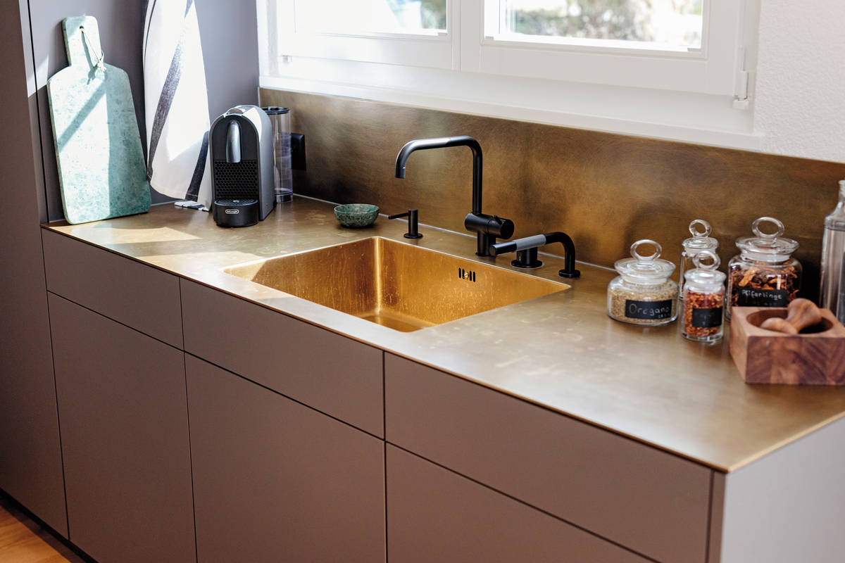 Der Trend zieht auch in der Küche ein: gebürstetes Messing. Kombiniert mit dunkler Oberfläche und Holz wirkt es edel und zeitlos. Herzog Küchen.