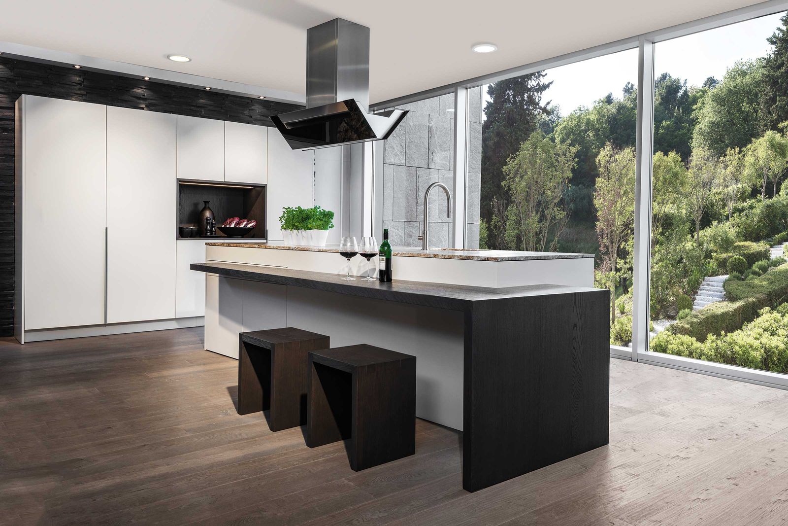 Beste Aussichten für echte Geniesser: Schlichte Kochinsel mit integrierter Bar in gebeizter Eiche, eleganten Hochschränken und offener Nische.