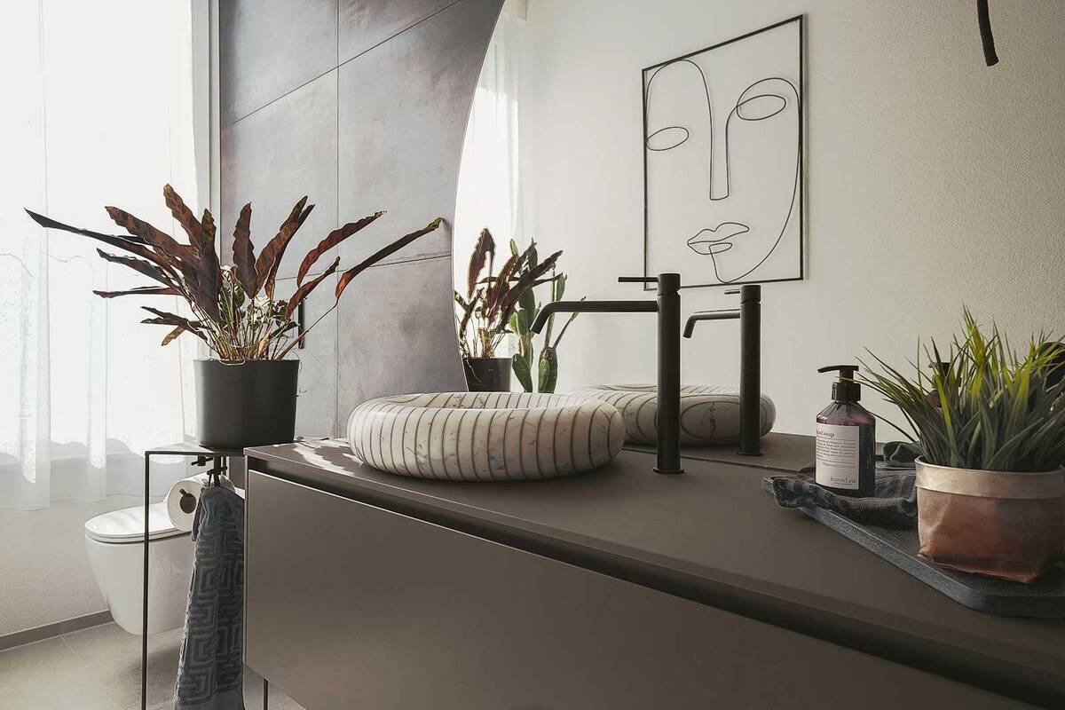 In diesem Badezimmer zieht ein echtes Schmuckstück die Blicke auf sich: Ein rundes Aufsatzbecken aus Carrara-Marmor, das mehr als nur ein funktionales Objekt ist – es ist ein Kunstwerk. Dazu passt mit seiner klaren Linienführung das Unterbaumöbel  &quot;Piana&quot; in Basalto mit einer Abdeckung aus Flumood, das praktischen Stauraum bietet. Die Waschtischarmatur «Via Tortona» von Gessi in mattem Schwarz setzt einen modernen Akzent. Hans Eisenring.