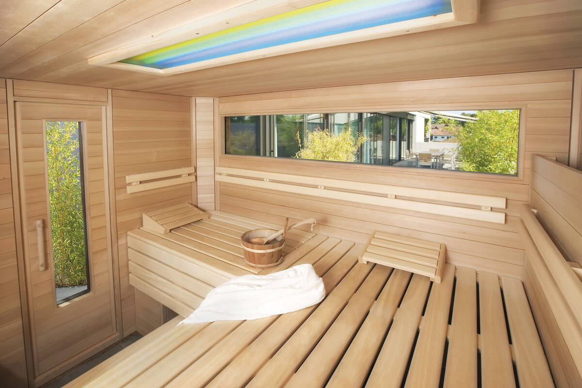 Von innen und aussen ein schöner Anblick: Auf die Terrasse abgestimmte Gartensauna von  Fitness-Partner AG.