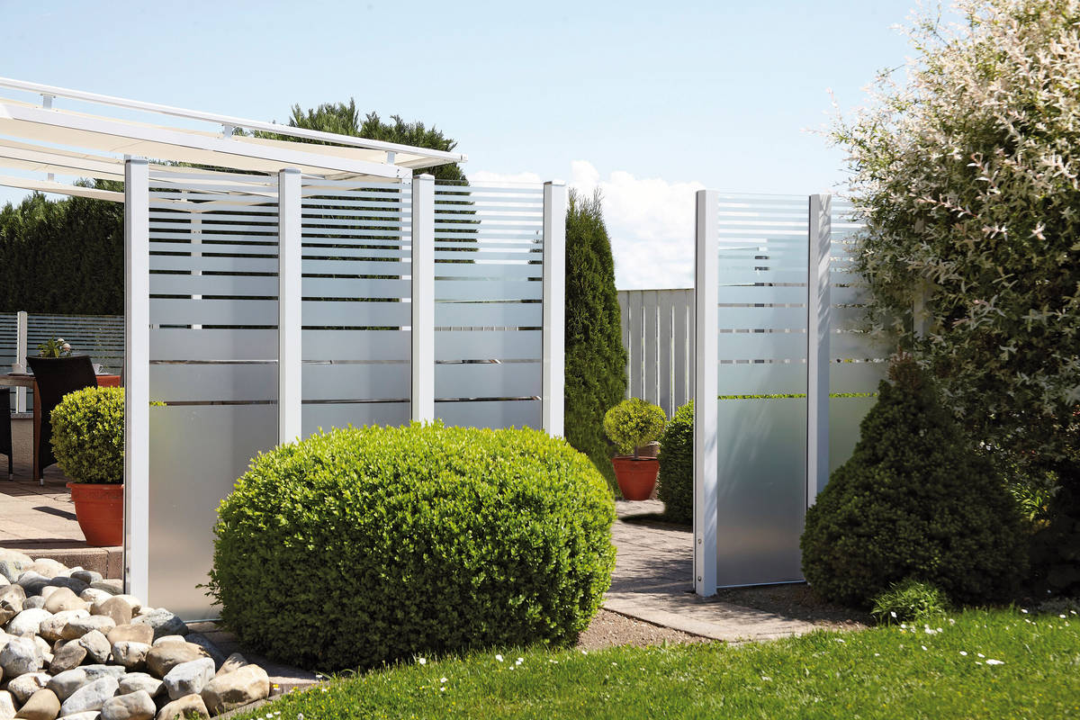 Glaswände schützen den Gartensitzplatz vor Zugluft und fremden Blicken, ohne Licht wegzunehmen. Tomwood.