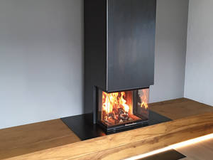 Schlicht schön: Diese Massanfertigung verbindet das Warmluftfeuermöbel aus Zunderstahl mit TV-Möbel und Schubladen. Baumann.