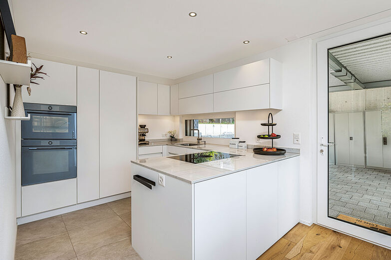 Die moderne Küche ist im Eck platziert und hat einen Zugang zum Carport.