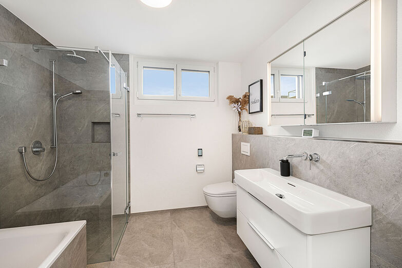 Das Bad wirkt mit bodengleicher Dusche und Glaswand geräumig.