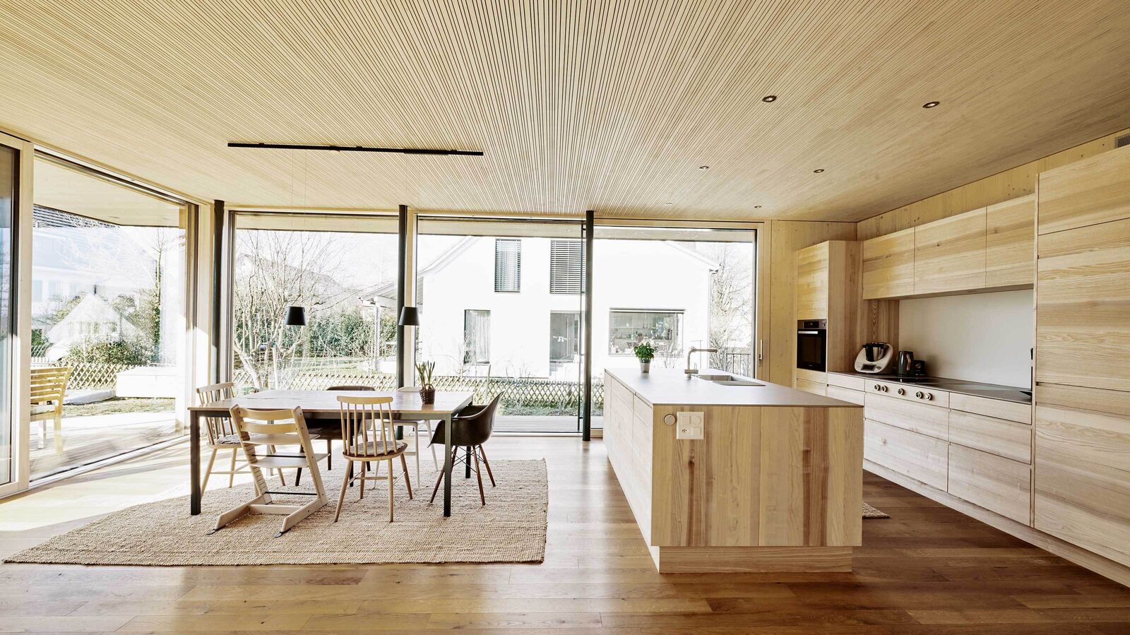 Grosse Fensterfronten schaffen Weite und setzen die Küche aus Eschenholz ins Rampenlicht.