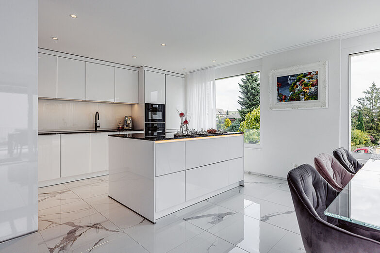 Die Lackfronten der Küche harmonieren mit dem edlen Fussboden. © Matthias Eberle Fotografie