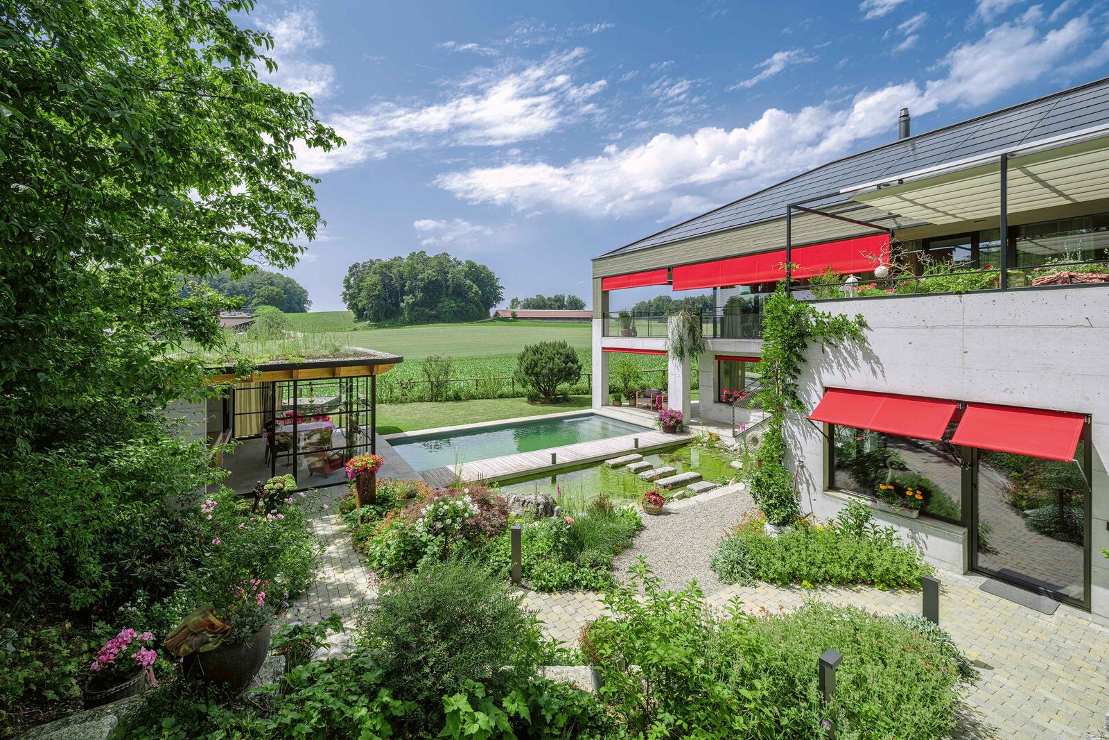 Eine Holzsteg zwischen Teich und Biopool führt zum Gartenpavillon.