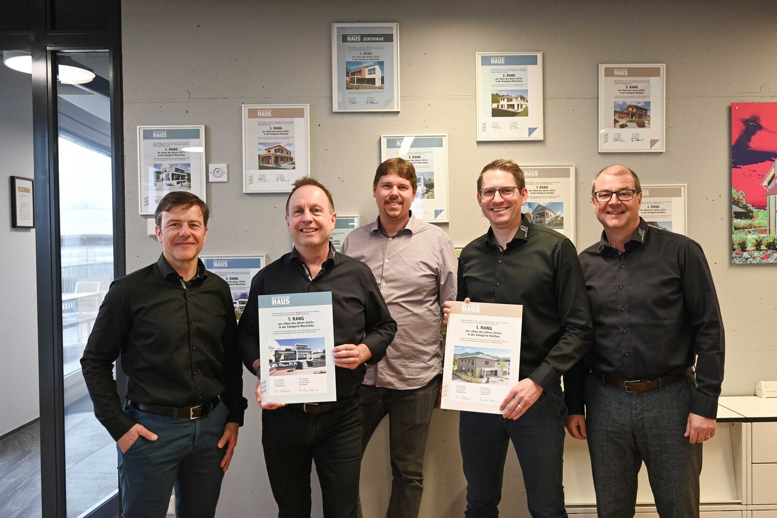 Zertifikatübergabe bei Kobelt für den 1. Rang in den Kategorien Holz- und Massivbau bei der Publikumswahl «Haus des Jahres 2023». Von links: Dominik Sieber (Geschäftsleiter), Bruno Dal Corobbo (Architekt Massivhaus), Marcel Hablützel (Head of Sales & Marketing, Etzel Verlag), Reto Ebneter (Architekt Holzhaus), Bruno Locher (Leiter Vertrieb und Architektur). Im Hintergrund ist zu sehen, dass die Kobelthäuser auch in den vergangenen Jahren vom Publikum gewürdigt wurden.
