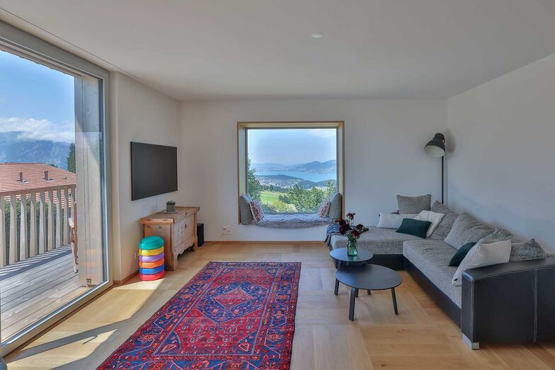 Ein besonderer Blickfang im Wohnzimmer ist das Sitzfenster mit dem raffinierten kupfernen Rahmen. Es zelebriert die grandiose Sicht auf den tiefblauen Fjordsee.