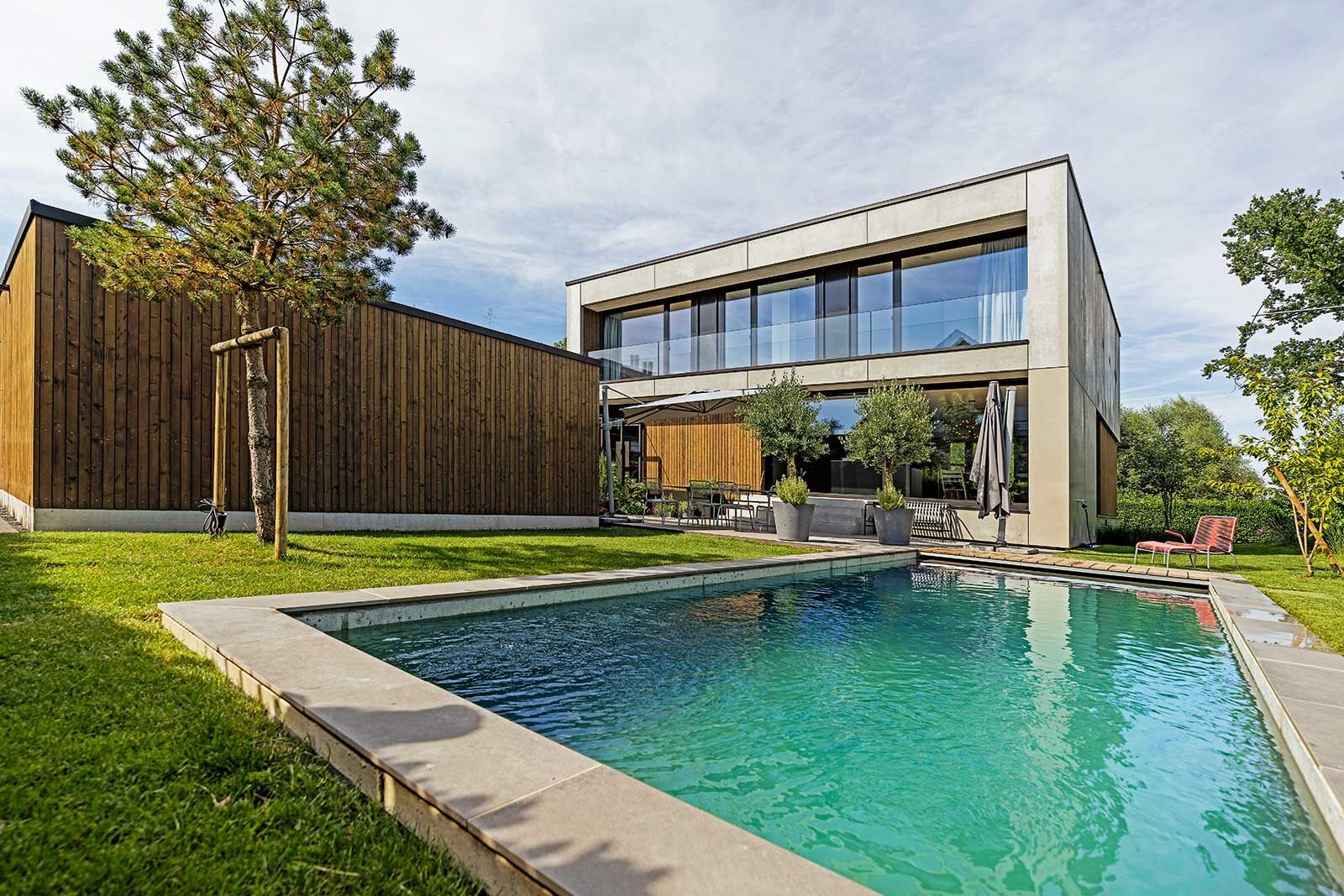 Der kubische Baukörper mit seiner Beton­elementfassade und Holzverkleidung ruht auf einem Hochparterre. Der Bodensee auf der Nordseite ist nicht nur in Sichtweite, er ist nicht mehr als einen ­Schilfstreifen vom Grundstück entfernt.
