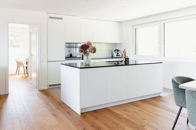 Die breite Fensterfront schafft Nähe zur Natur und macht den Küchenarbeitsplatz hell.