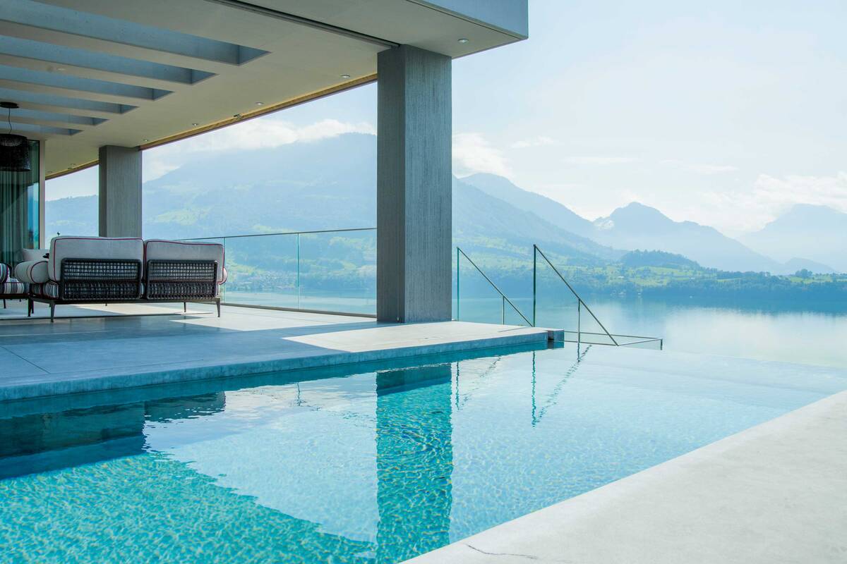 Beim Betonpool mit Panzerglas geniesst man wortwörtlich eine glasklare Aussicht. Die betonierte Treppe führt ins erfrischende Nass, eine Sitzbank sorgt für zusätzlichen Komfort. Nachts kann der Pool dank der Unterwasserbeleuchtung in Szene gesetzt werden. Zireg Ziswiler GmbH.