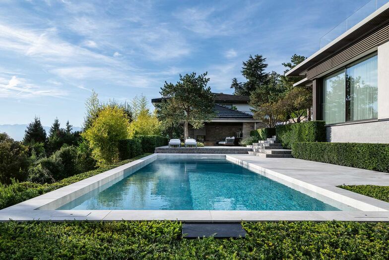 Im Pool spiegelt sich der Himmel, dichte grüne Hecken gliedern den Garten, schaffen Verbindungen und Räume.