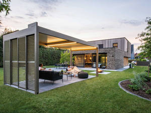 Das Lamellendach kann durch eine senkrechte Markise ergänzt werden. Es sorgt nicht nur für angenehmen Schatten, sondern zudem für einen guten Sichtschutz. Atrium über Renson.