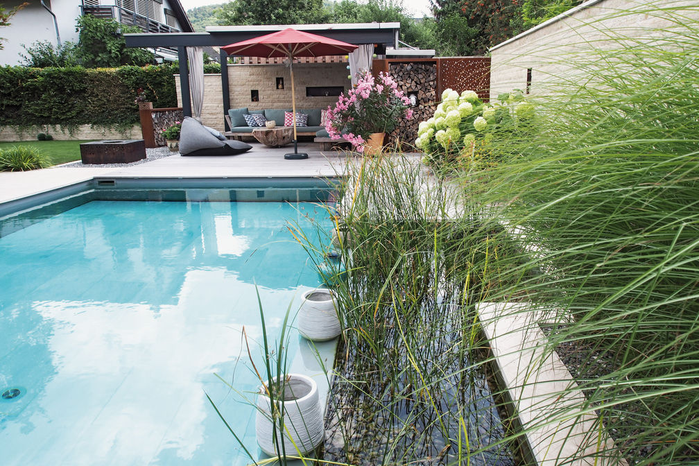 Gut integriert: Ein Umbauprojekt, das den Garten aufwertet: Der neue Biopool und die Sauna machen ihn zur Wellnessoase. Die bestehende Pergola wurde renoviert und mit einer Mauer versehen. Eine weitere Mauer dient als Sichtschutz zum Nachbarn. Brunnen, Bepflanzung und Beleuchtung werten den Sitzplatz auf und komplettieren die Erholungszone. Wetzel AG.