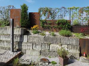 Eisenplatten, kombiniert mit rostigen Rankgittern, ergeben ein lockeres, spannungsvolles Gesamtbild. Abderhalden Gartenbau AG.