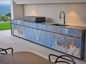 Die «Avers Outdoorküche» von Theiss verspricht gemütliche Grillstunden: «Bookmatch»-Keramikplatten, ein pulverbeschichteter Edelstahlkorpus sowie eine LED-Beleuchtung unter der Arbeitsfläche sind Hingucker dieser wetterbeständigen Outdoorküche. Theiss by Lynx Group GmbH.