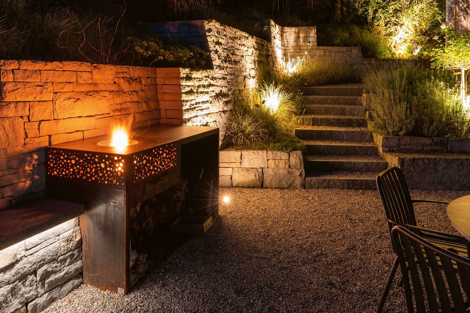 Flamma Magna vereint romantisches Feuer mit kulinarischem Genuss und ist genau richtig für ein geselliges Beisammensein. Die urtümliche Schönheit des Feuers leuchtet durch die ziselierten Stahlseiten, auf der Edelstahlfläche rund um das Feuer lässt sich kochen und grillieren. Eine zusätzliche Ablagefläche rechts oder links sowie ein Holzdepot unten ergänzen das Modell. www.flammengrill.ch