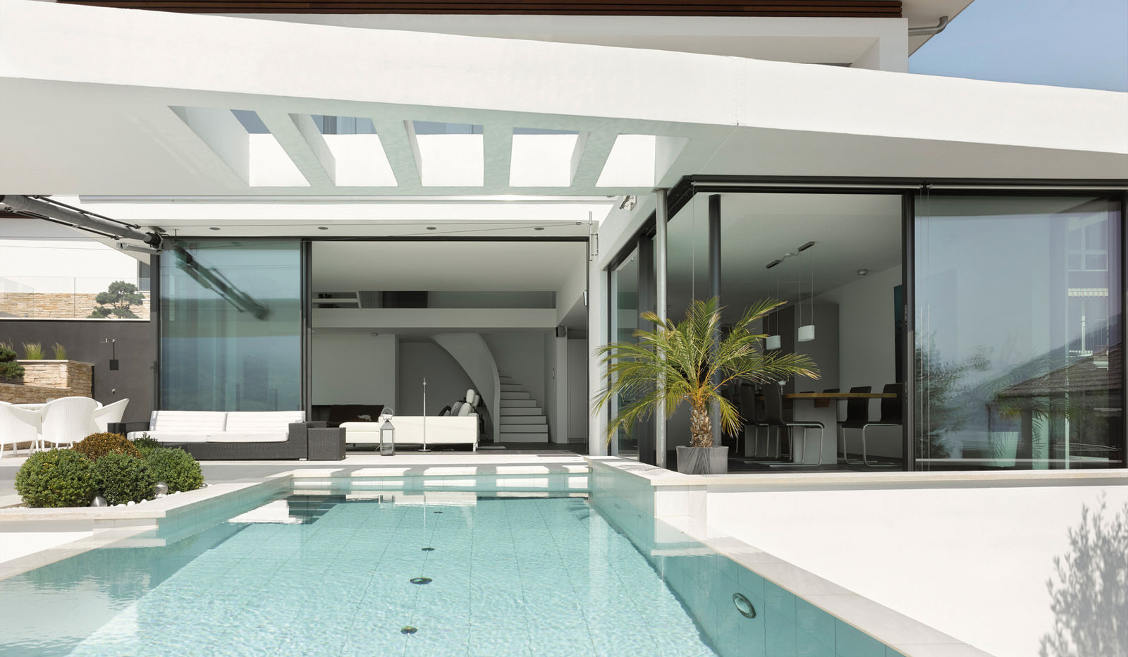 Mondän am Hang: Der sechs Meter lange Pool mit Gegenstromanlage ist zum Schwimmen bestens geeignet. Optisch bildet er eine Einheit mit den Wohnräumen im Erdgeschoss und begeistert als zentrales Element einer spektakulären Architektur. Vivell + Co AG.