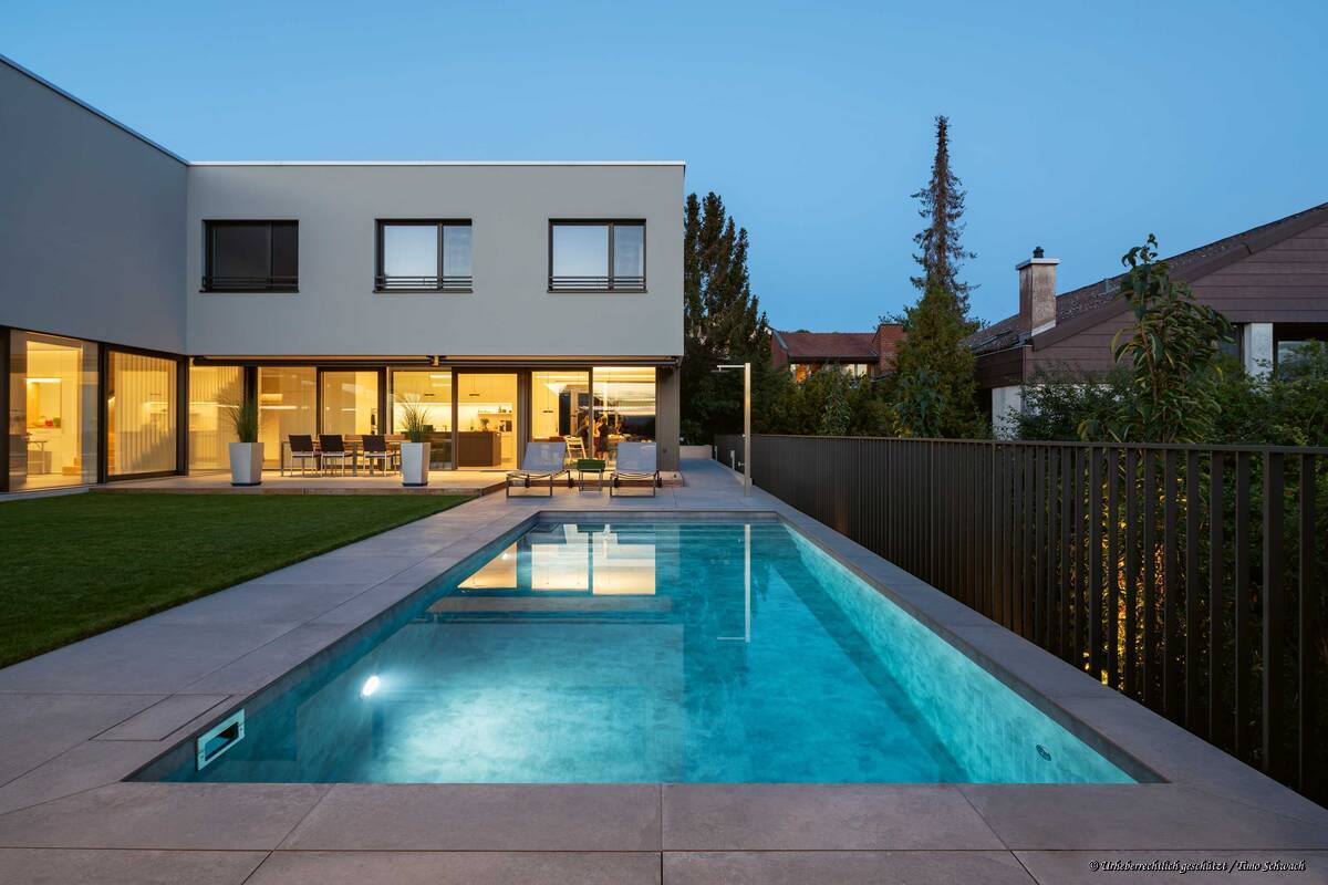 Das Beton-Becken mit Granit-Umrandung wird abends mit Unterwasserscheinwerfern in stimmungsvolles Licht getaucht. Es verfügt unter anderem über eine vollautomatische, chlor- und salzfreie Wasseraufbereitungsanlage. Foto: Timo Schwach. AC Schwimmbadtechnik AG. 