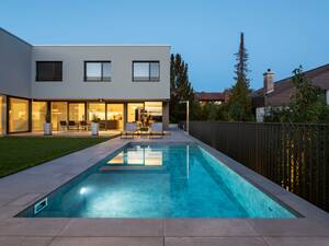 Das Beton-Becken mit Granit-Umrandung wird abends mit Unterwasserscheinwerfern in stimmungsvolles Licht getaucht. Es verfügt unter anderem über eine vollautomatische, chlor- und salzfreie Wasseraufbereitungsanlage. Foto: Timo Schwach. AC Schwimmbadtechnik AG. 