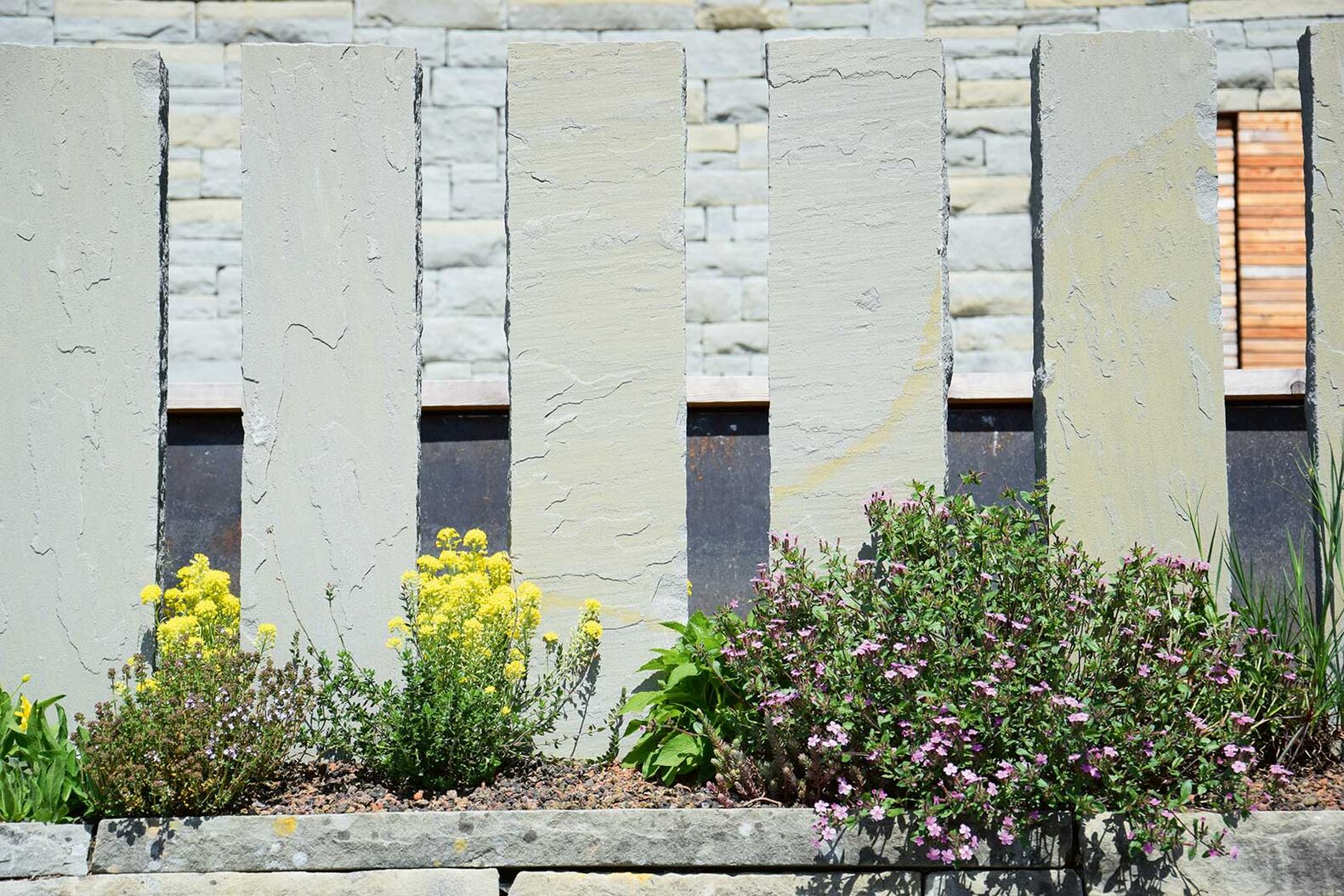 Die Schweizer Sandsteinstehlen vom Steinbruch Bärlocher werden als Sichtschutz eingesetzt und machen sich im Garten besonders schön in Kombination mit farbigen Blumen. Die Höhe und der Abstand der Stehlen sind frei wählbar. Abderhalden Gartenbau AG, www.abderhalden.ch