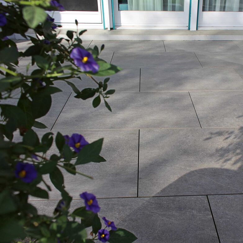 Feinsteinzeug: Der kleine Sitzplatz eines Doppel-Einfamilienhauses wurde mit grossformatigen Platten ausgelegt. Sie sind pflegeleicht, kratz- und stossfest, frostbeständig und nahezu wartungsfrei. Die Robustheit des Materials eröffnet eine grosse Freiheit für unterschiedliche Nutzungen – von Essplatz, Lounge oder Grillplatz bis hin zum Spielparadies für Kinder oder als sportliches Terrain für die Tischtennisrunde. www.ganz-baukeramik.ch