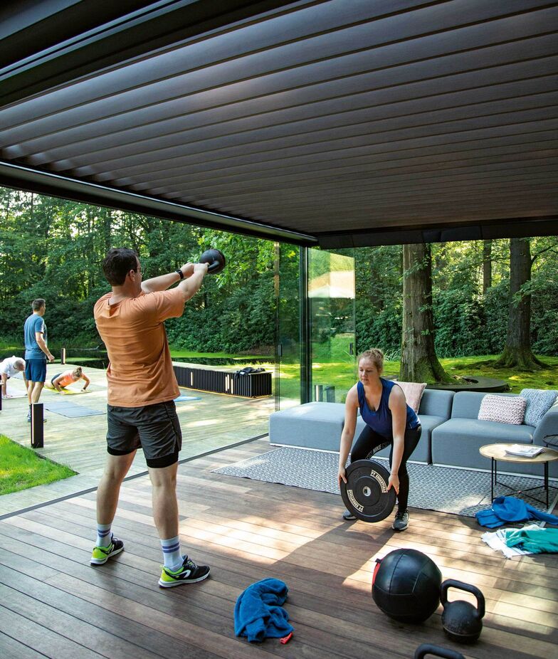 Die Terrassenüberdachung im Garten eignet sich auch als Fitnesscenter bestens. Mit Beleuchtung, Heizelementen, Sound und genau so viel Sonne und Schatten wie gewünscht. Renson, www.renson-outdoor.com