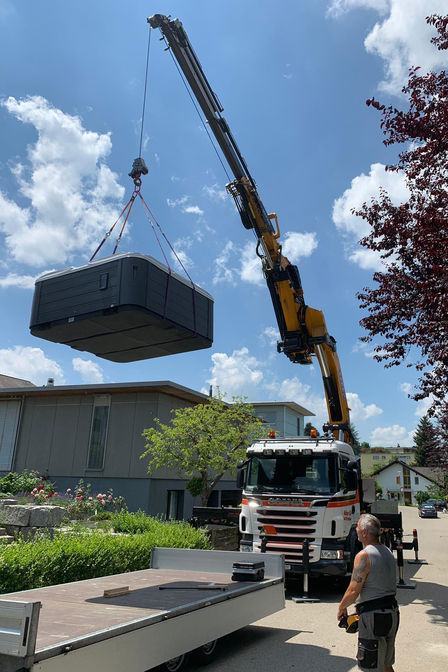 Unter den Blicken der staunenden Nachbarschaft hievt ein Kran den Pool über die Gartenmauer. 