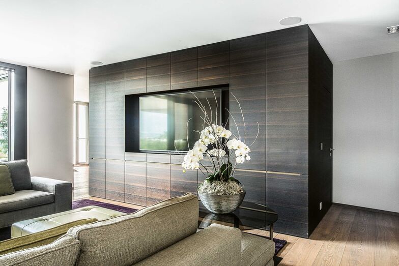 Ganzheitlich gedacht: Beim Innenausbau dieses Hauses wurde ganzheitlich gedacht und geplant. Die Wahl fiel auf dunkle Räuchereiche, welche dem intelligenten, einheitlichen Design Konsistenz und der Wohnung selbst viel Wärme verleiht. Das Material zieht sich durchs ganze Haus und ist unter anderem bei der Wohnwand im Wohnzimmer, beim Bücherregal und in der ans Schlafzimmer grenzenden Ankleide anzutreffen. Stuber Team AG, www.stuberteam.ch