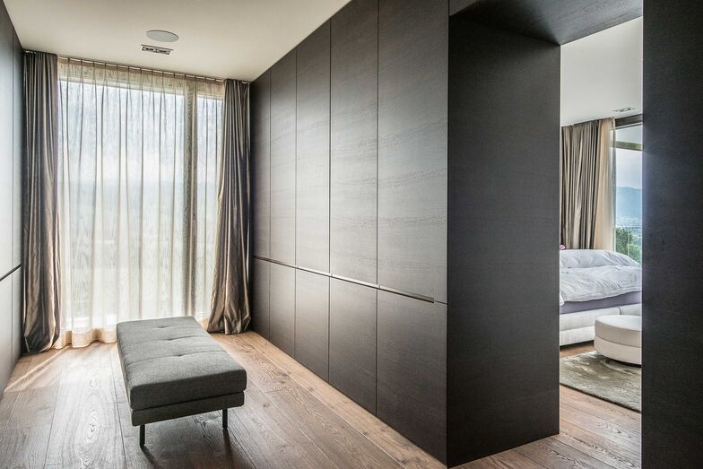 Ganzheitlich gedacht: Beim Innenausbau dieses Hauses wurde ganzheitlich gedacht und geplant. Die Wahl fiel auf dunkle Räuchereiche, welche dem intelligenten, einheitlichen Design Konsistenz und der Wohnung selbst viel Wärme verleiht. Das Material zieht sich durchs ganze Haus und ist unter anderem bei der Wohnwand im Wohnzimmer, beim Bücherregal und in der ans Schlafzimmer grenzenden Ankleide anzutreffen. Stuber Team AG, www.stuberteam.ch