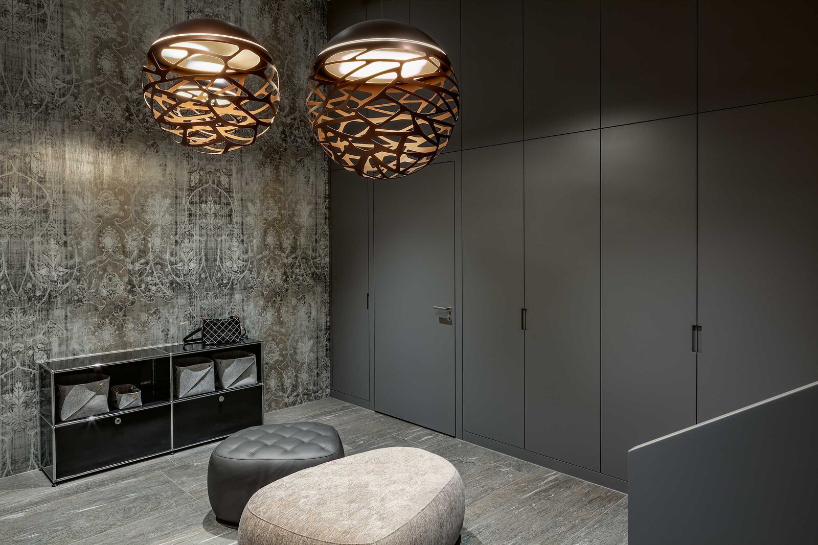 Eleganz im Entrée: Der fast vier Meter hohe Raum mit der schönen Tapete und der guten Beleuchtung hat eine wunderbare Stimmung. Die grosse dunkle Schrankfront nimmt sich dezent zurück, bietet aber viel Stauraum in den Garderobeschränken und darüber. In die Front integriert ist die Tür zum Keller. Unter der Treppe befinden sich weitere, abgeschrägte Schränke. Kreativschreinerei Wagner AG, www.kreativschreinerei.ch