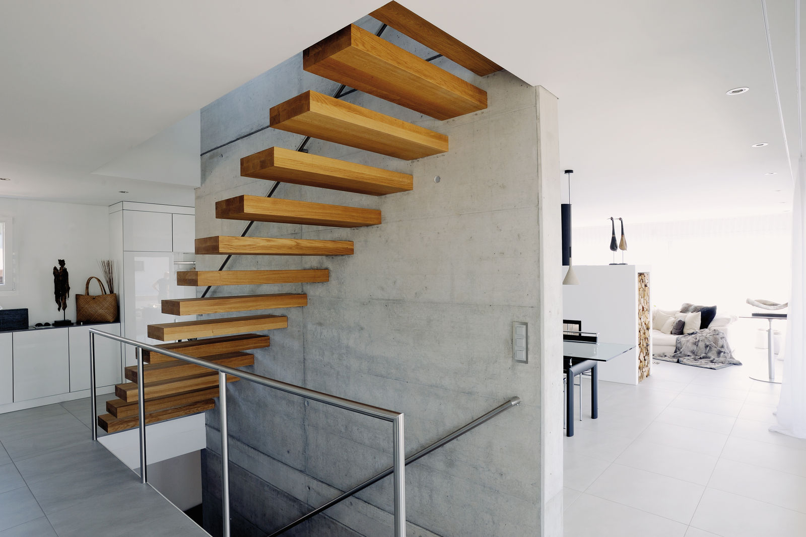 Stufen aus europäischer Eiche freitragend an Betonwand. Handlauf und Geländer CNS geschliffen.