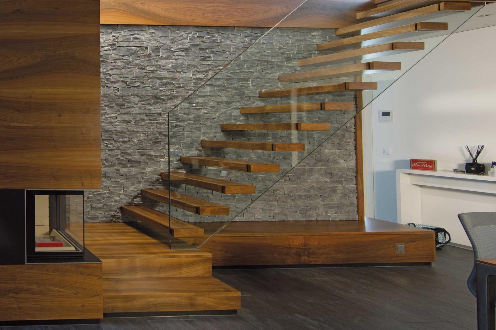 Die Stufen aus amerikanischem Nussbaum scheinen zwischen der Wand und der Glasbrüstung zu schweben. Keller Treppenbau AG.