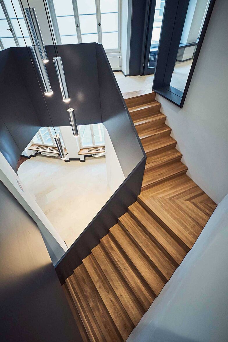 Ein Blick von oben: Die Kombination aus warmem Holz und mattschwarzem Geländer verleiht dieser Treppe einen zeitlosen und eleganten Charakter. Columbus Treppen AG, www.columbus.ch