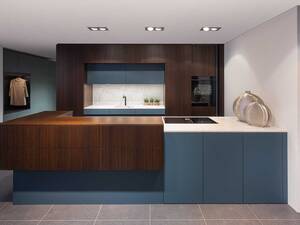 Elbau kombiniert dunkle Räuchereiche und petrolblaue Fronten. Aufgebrochen werden die dunkleren Elemente mit einer Abdeckung und einem Becken aus italienischem Naturstein. Dieser wird mit einer LED-Beleuchtung noch stärker hervorgehoben und betont die natürliche Marmorierung des Steins. Elbau Küchen AG.