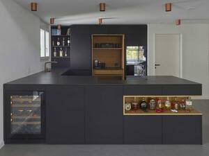 Bei diesem Küchenumbau wurden mattschwarze Fronten mit einer grosszügigen Nische in Eiche massgefertigt. Die LED-Beleuchtung und die mattschwarzen Griffprofile aus Aluminium erzeugen eine visuell ansprechende Komposition. Oesch Innenausbau AG.