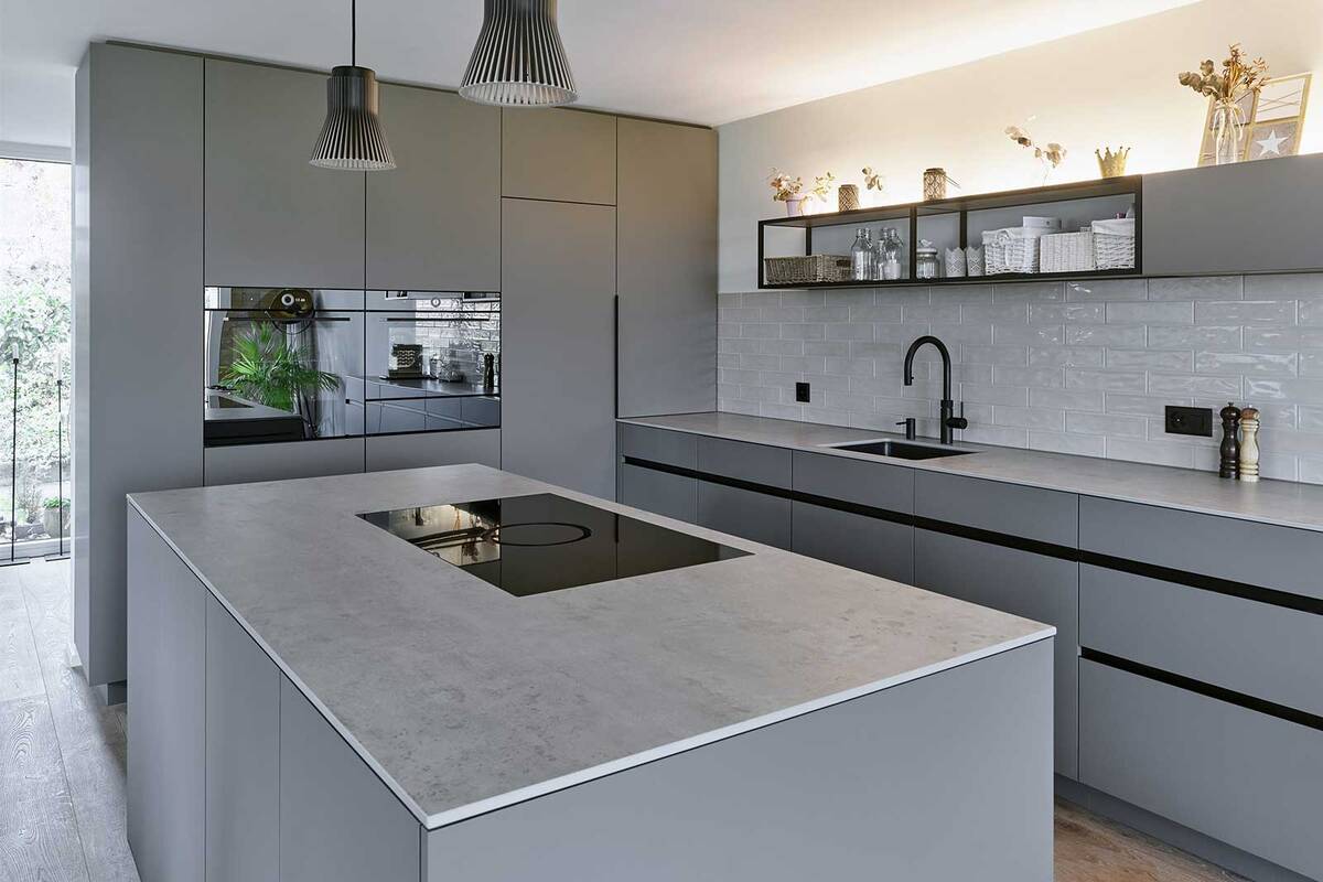 Die offenen Metalloberbauten mit schwarzen Aluprofilen erinnern an den Industrielook. Die schlichte Küche mit integriertem LED-Streifenlicht ist nach Kundenwünschen massgeschneidert. Oesch Innenausbau.