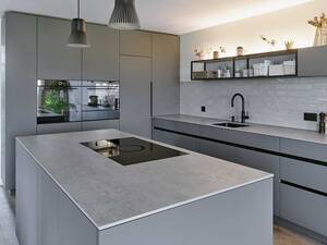 Die offenen Metalloberbauten mit schwarzen Aluprofilen erinnern an den Industrielook. Die schlichte Küche mit integriertem LED-Streifenlicht ist nach Kundenwünschen massgeschneidert. Oesch Innenausbau.