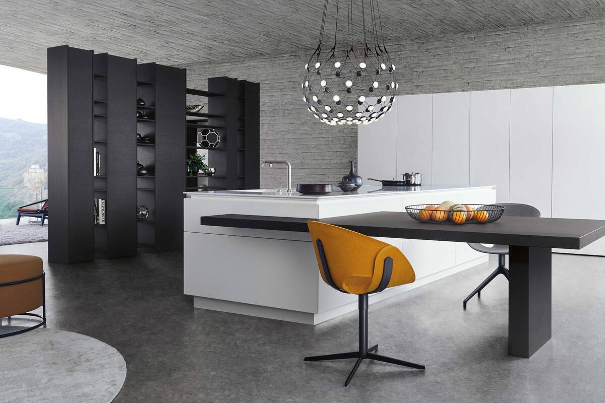 Der grifflose Inselblock und der in dunklem Holz gehaltene Sitzbereich verschmelzen elegant miteinander. Ein durch offene und geschlossene Regal- und Schrankeinschübe untergliedertes Element kommt als Raumteiler zum Einsatz. Foto: Leicht Küchen AG. Fust.